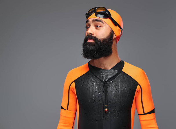 Portrait of a bearded male in orange neoprene diving suit and dive mask isolated on grey background. - Photo, Image
