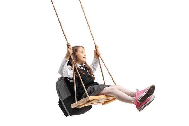 Little schoolgirl swinging on a wooden swing isolated on white background - Foto, Imagem