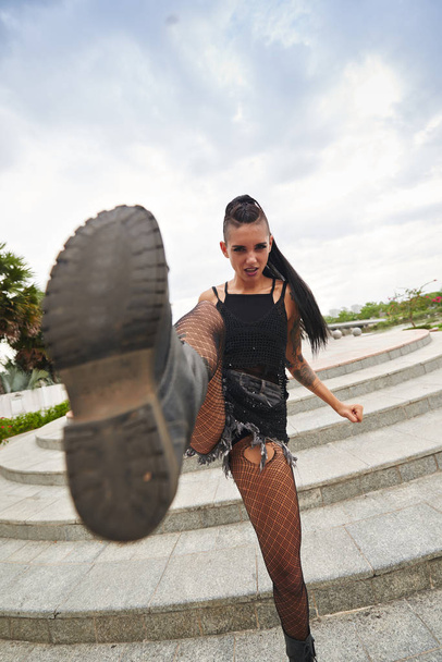 Rebellious young pretty punk girl kicking camera - Fotografie, Obrázek