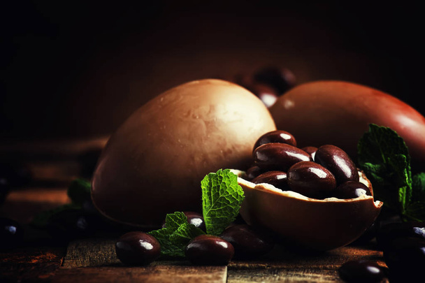 Easter composition with brown chocolate eggs, vintage wooden background, selective focus - Fotó, kép