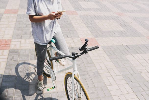 Cropped image of girl on bicycle checking smartphone - Photo, Image