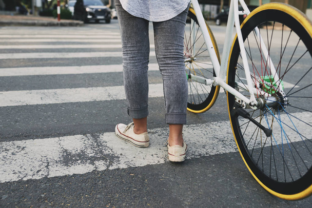 Junge Frau überquert mit Fahrrad breite Straße - Foto, Bild