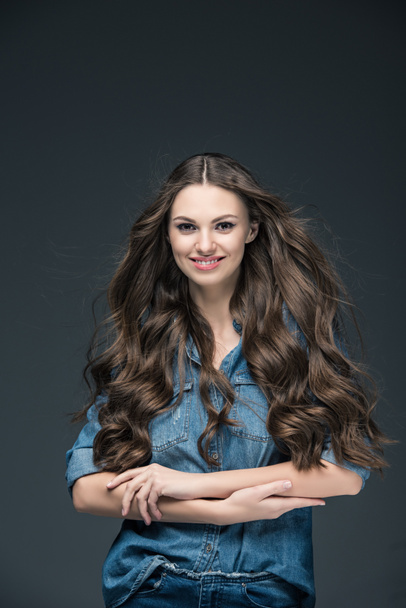 hermosa chica alegre con el pelo largo posando en camisa de mezclilla, aislado en gris
 - Foto, Imagen