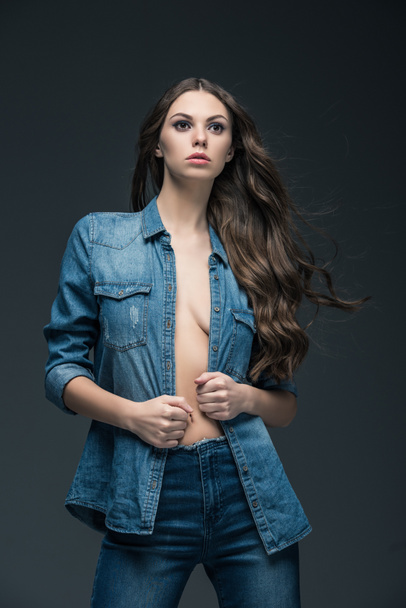 sexy girl with long hair posing in denim shirt, isolated on grey  - Foto, imagen