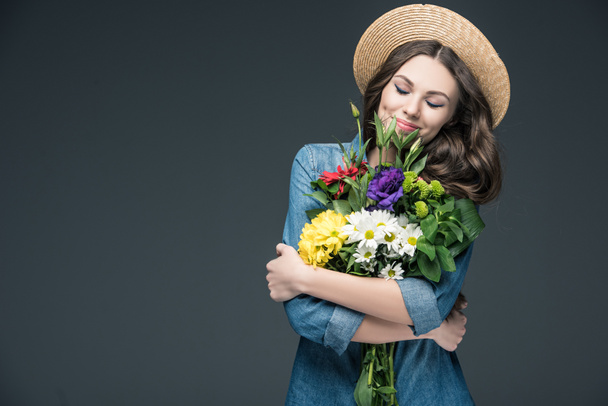 piękna kobieta szczęśliwa z zamkniętymi oczami gospodarstwa kwiaty do 8 marca, na szarym tle - Zdjęcie, obraz