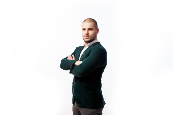 Ein glatzköpfiger Geschäftsmann in weißem Hemd, grünem Anzug blickt selbstbewusst in die Kamera und hält vor weißem Hintergrund die Arme verschränkt auf der Brust. - Foto, Bild