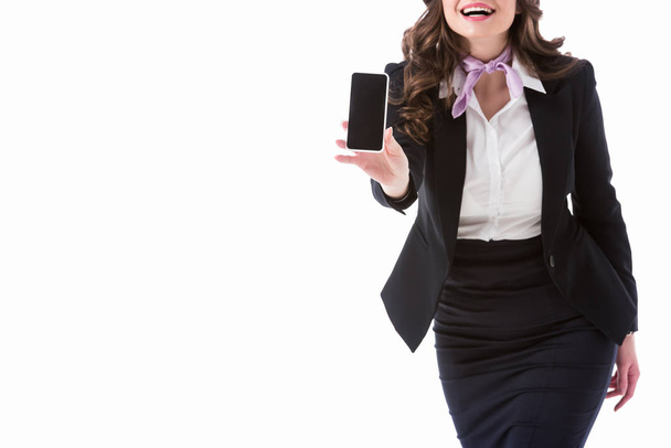 cropped image of laughing stewardess showing smartphone with blank screen isolated on white - Foto, Imagem