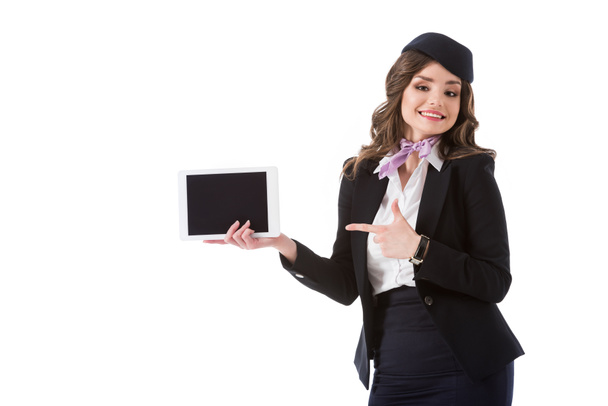 aantrekkelijke stewardess wijzen op tablet met leeg scherm geïsoleerd op wit - Foto, afbeelding