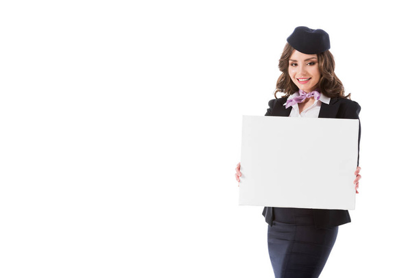 smiling attractive stewardess holding empty board isolated on white - Foto, imagen