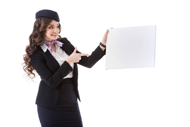 beautiful stewardess pointing on empty board isolated on white - Фото, изображение