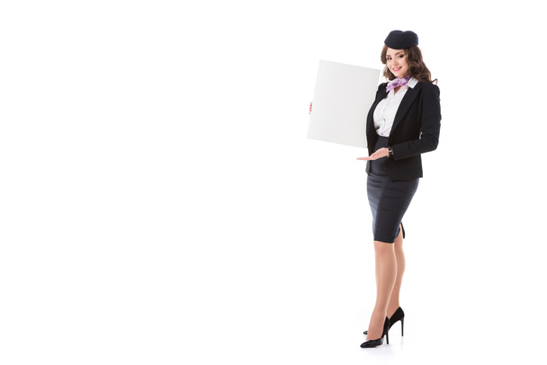 attractive stewardess holding empty board and looking at camera isolated on white - Zdjęcie, obraz