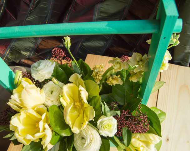 Arranjo de flores de primavera em uma caixa de madeira verde com uma barra transversal
, - Foto, Imagem