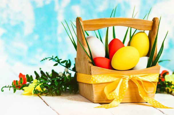 Easter spring composition, basket with painted colorful eggs and grass around. Close up portrait on sky background. - Foto, immagini
