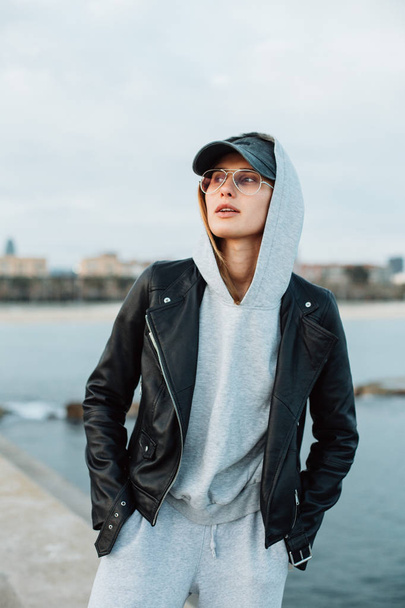 portrait of young woman in grey hoodie and sweatpants standing on pier - Photo, image