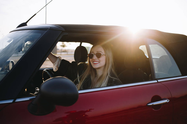 Portret młodej kobiety siedzi w samochodzie o zachodzie słońca - Zdjęcie, obraz