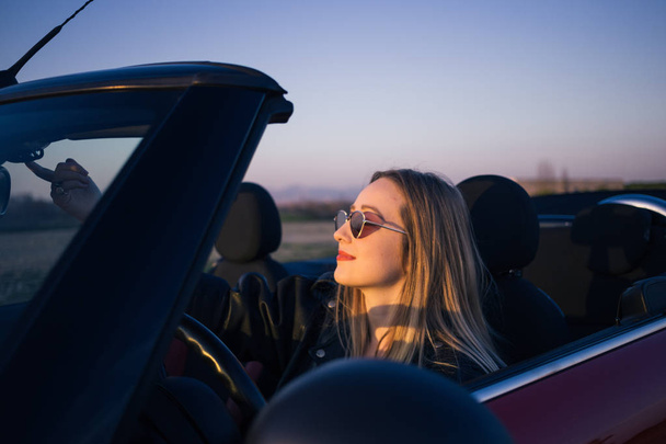 gün batımında arabada oturan genç kadın portresi - Fotoğraf, Görsel
