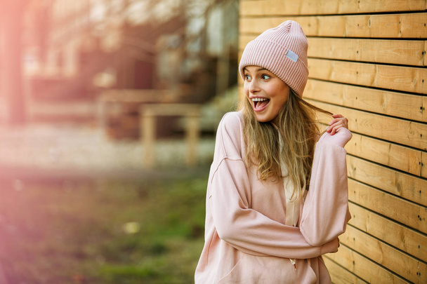 cool young woman in pink hoodie on wooden background - Фото, зображення