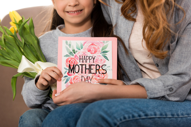 cropped shot of mother and daughter holding yellow tulips and happy mothers day greeting card - Photo, image