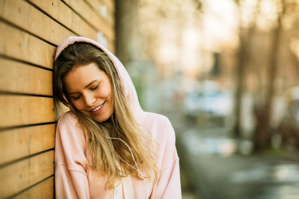 cool young woman in pink hoodie on wooden background - Fotó, kép
