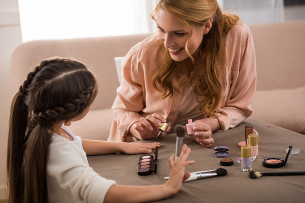 happy mother and little daughter applying makeup together at home  - Photo, Image