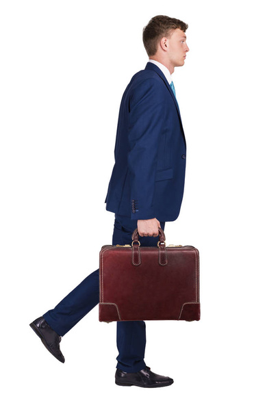 Бизнесмен в прекрасном костюме держит в одной руке чемодан, ходит т
 - Фото, изображение