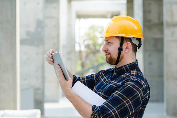 Ingeniero masculino en un sitio de construcción con una tableta  - Foto, imagen