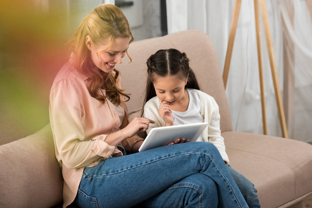 happy mother and daughter using digital tablet together at home  - Foto, afbeelding