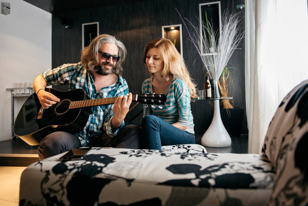 Romantic man with glasses and beard playing guitar for his woman - Fotografie, Obrázek