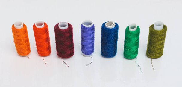 en una fila hay bobinas de hilo multicolores diseñados para la aguja
 - Foto, Imagen