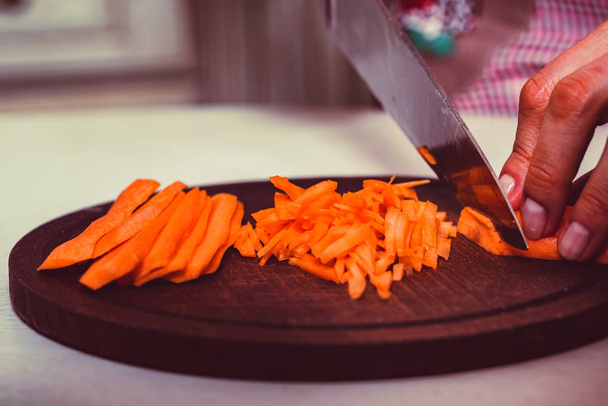 Les femmes mains tranchent la carotte sur une planche en bois
 - Photo, image