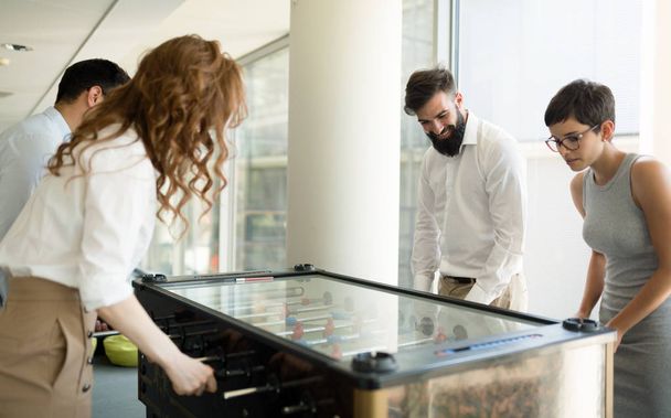 Coworkers playing table football together on break from work - Fotoğraf, Görsel