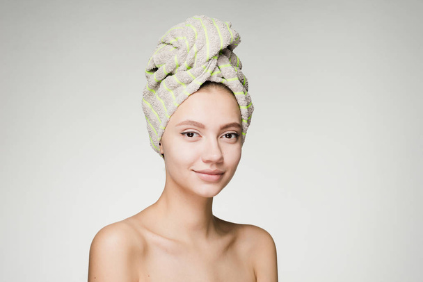 a surprised woman with a towel on her head against a gray background - Foto, imagen