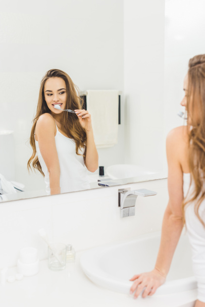 young woman brushing teeth in morning at home - Фото, изображение