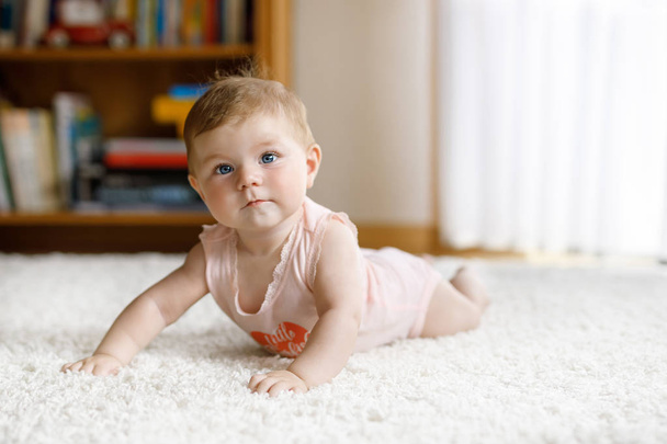 Kleine lustige Babymädchen heben Körper und lernen zu kriechen. - Foto, Bild