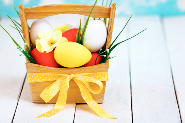 Easter spring composition, basket with painted colorful eggs. Close up portrait on sky background. - Фото, зображення