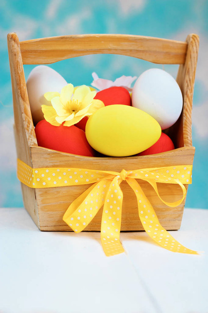 Easter spring composition, basket with painted colorful eggs. Close up portrait on sky background. - Фото, изображение