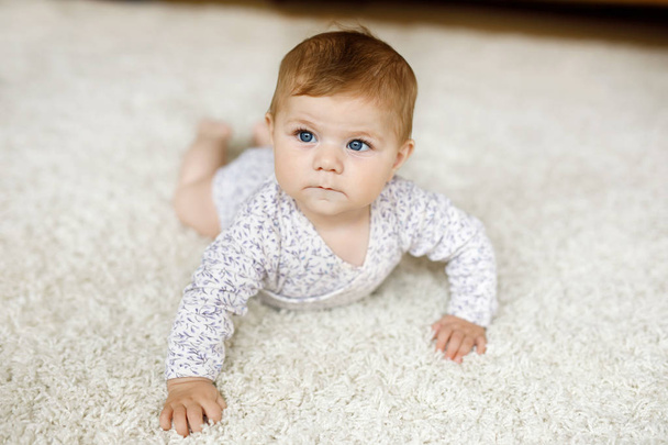 Little funny baby girl lifting body and learning to crawl. - Fotó, kép