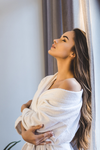 side view of attractive young woman in bathrobe at home - Photo, Image