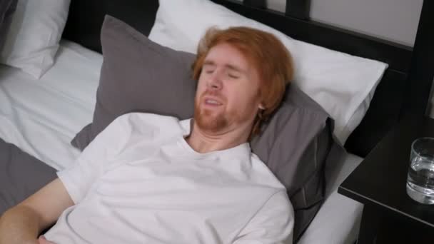 Κοκκινομάλλης άντρας ξαπλωμένη στο κρεβάτι που αισθάνονται άβολα, αναταραχή - Πλάνα, βίντεο