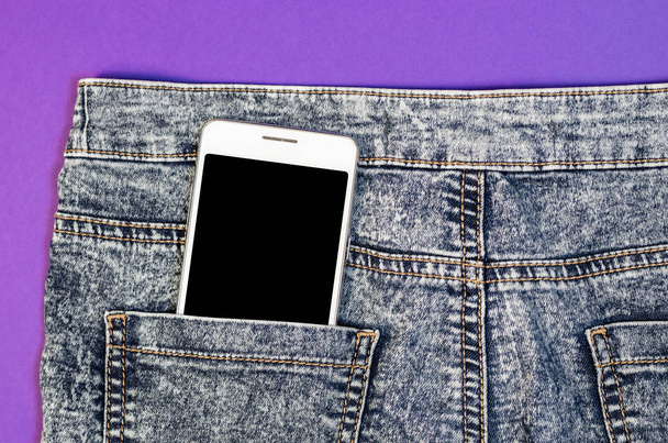 Close Up Bussines Fashion Stylish Smart Phone Screen Copy Space White Mobile in Black Jeans Back Pocket Denim Hipster on ultra violet trend color background - Photo, Image