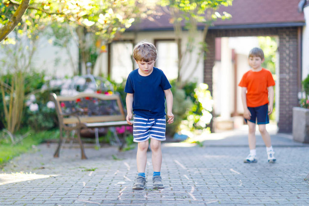 Two little school and preschool kids boys playing hopscotch on playground - Photo, Image