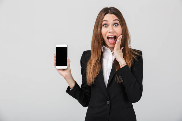 Beautiful lady with opened mouth and showing smartphone with blank screen isolated - Фото, зображення