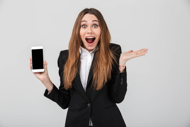 Beautiful lady with opened mouth and showing smartphone with blank screen isolated - Zdjęcie, obraz