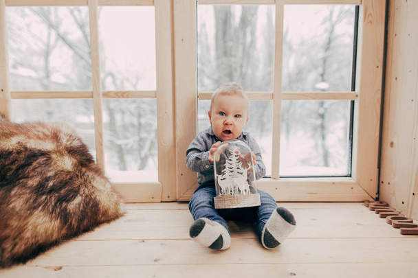 portrait of baby boy sitting with toy on wooden window sill - Photo, Image