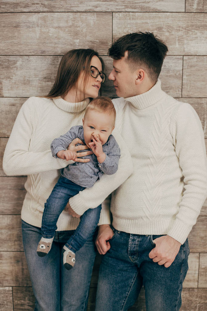 portrait of young couple with baby boy standing on wooden background - Photo, image