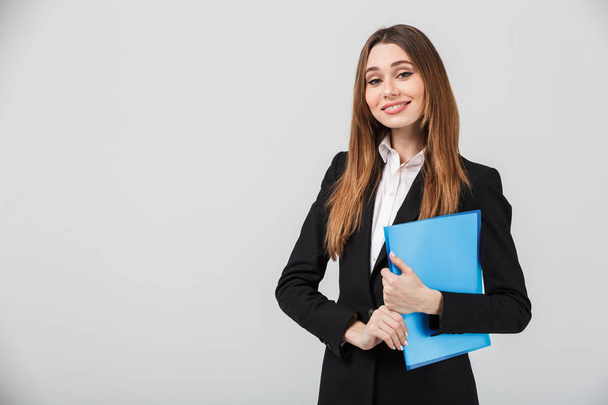 Cheerful businesswoman holding folder and smiling to camera - Fotó, kép