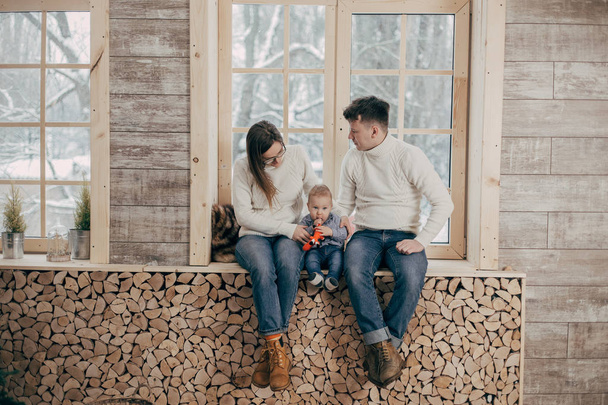 portrait of young couple with baby boy sitting on wooden window sill - Photo, Image