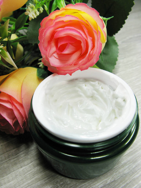 cosmetische crème voor gezichts onderhoud en roze bloemen  - Foto, afbeelding