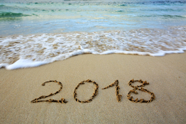 Рік 2018 написано на піщаному пляжі з морською хвилею
 . - Фото, зображення