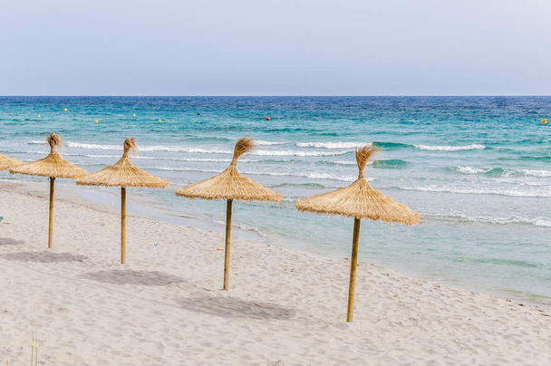 Ψάθινες ομπρέλες σε παραλία με άμμο. - Φωτογραφία, εικόνα
